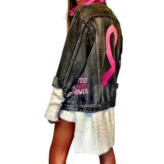 Faded black denim. Pink ombre Breast Cancer ribbon painted in large on back. Love, Strength, Trust, Beauty, Peace, Hope, Passion, Faith, Power painted in light & bright pink on the front. Collar painted in pink ombre. Signed @wrenandglory.