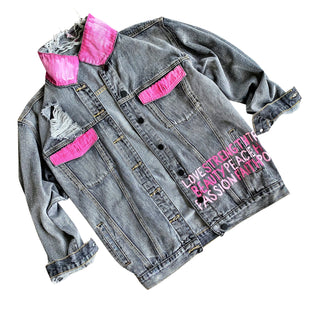 Faded black denim. Pink ombre Breast Cancer ribbon painted in large on back. Love, Strength, Trust, Beauty, Peace, Hope, Passion, Faith, Power painted in light & bright pink on the front. Collar painted in pink ombre. Signed @wrenandglory.