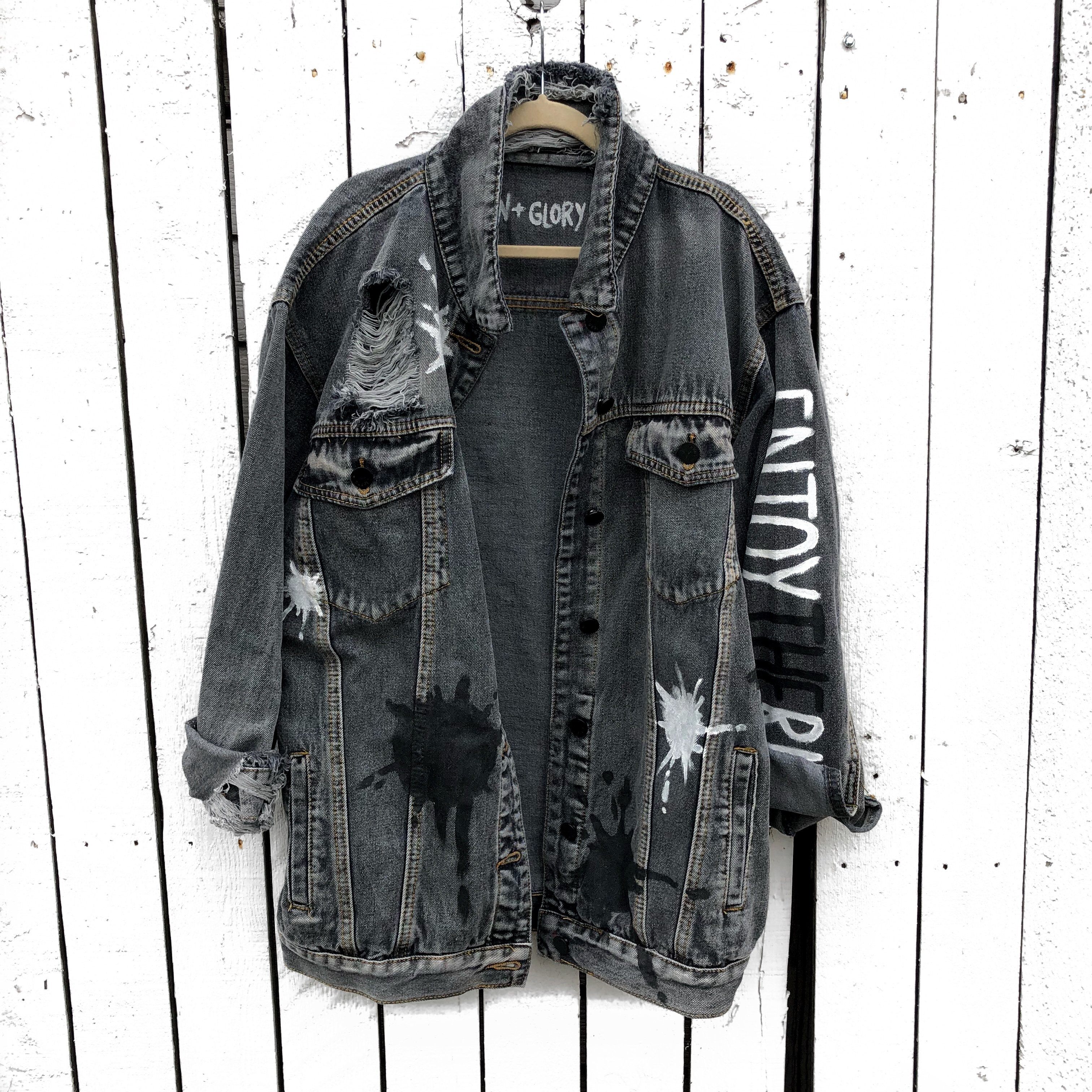 Faded black denim wash. Large white initial on back, with painted white and black 'splatters' 'Enjoy The Ride' painted in black and white down the arm. Signed @wrenandglory.