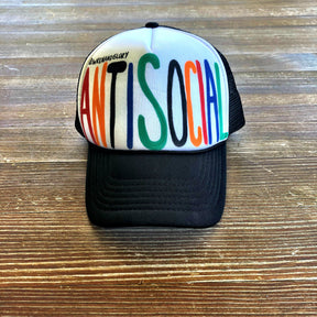White and black trucker hat. Hand painted ANTI SOCIAL in multi colors. Signed @wrenandglory