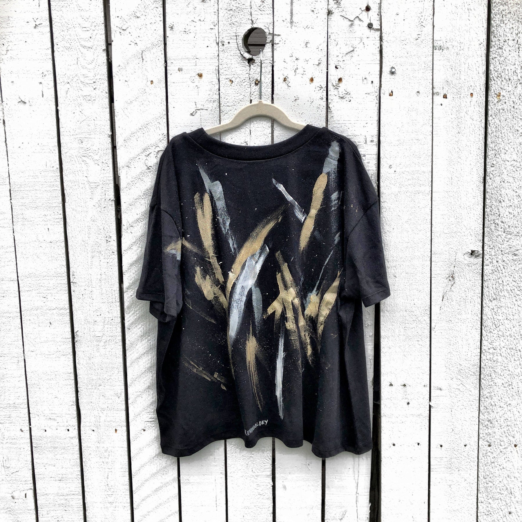 The perfect cropped black T shirt. Assorted color metallics and white splatter and stripes painted on back, with small stars painted on front, upper left side in gold. Signed @wrenandglory.