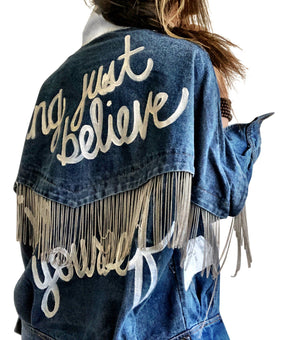 Darker blue denim wash with silver chains. 'DARLING JUST BELIEVE IN YOURSELF' painted in white script on back. Color and front pockets painted white. Signed @wrenandglory.