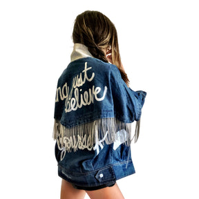 Darker blue denim wash with silver chains. 'DARLING JUST BELIEVE IN YOURSELF' painted in white script on back. Color and front pockets painted white. Signed @wrenandglory.