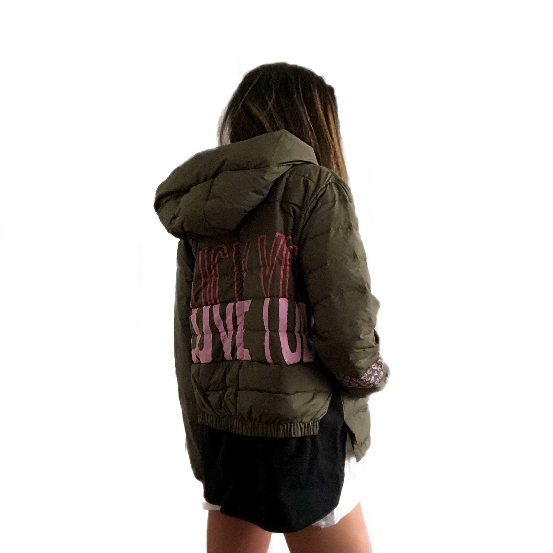 Perfect army green puffer jacket. On back, painted 'LOVE/FCK YOU' in pink and red. Bottom on left sleeve painted with pink hearts all around. Signed @wrenandglory.
