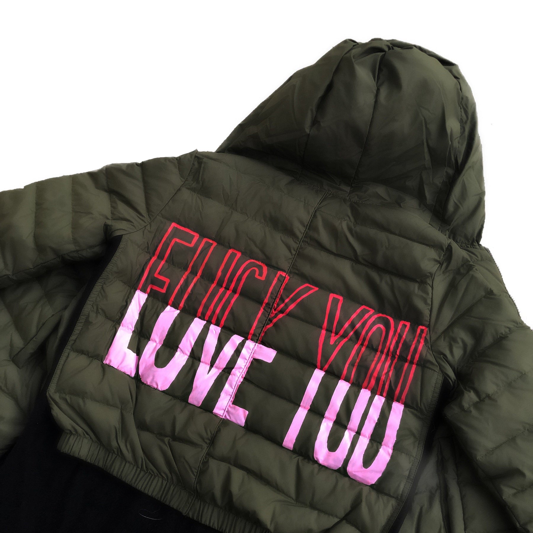 Perfect army green puffer jacket. On back, painted 'LOVE/FCK YOU' in pink and red. Bottom on left sleeve painted with pink hearts all around. Signed @wrenandglory.