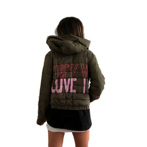 Perfect army green puffer jacket. On back, painted 'LOVE/FCK YOU' in pink and red. Bottom on left sleeve painted with pink hearts all around. Signed @wrenandglory.