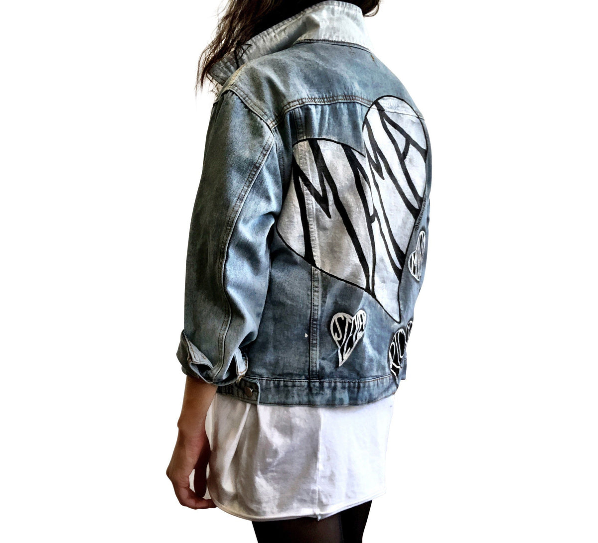 Lighter blue denim wash. Large white heart on back with MAMA painted inside in black. Smaller black hearts surrounding the larger one, customized with kids names. Collar and front pockets painted white. Signed @wrenandglory.